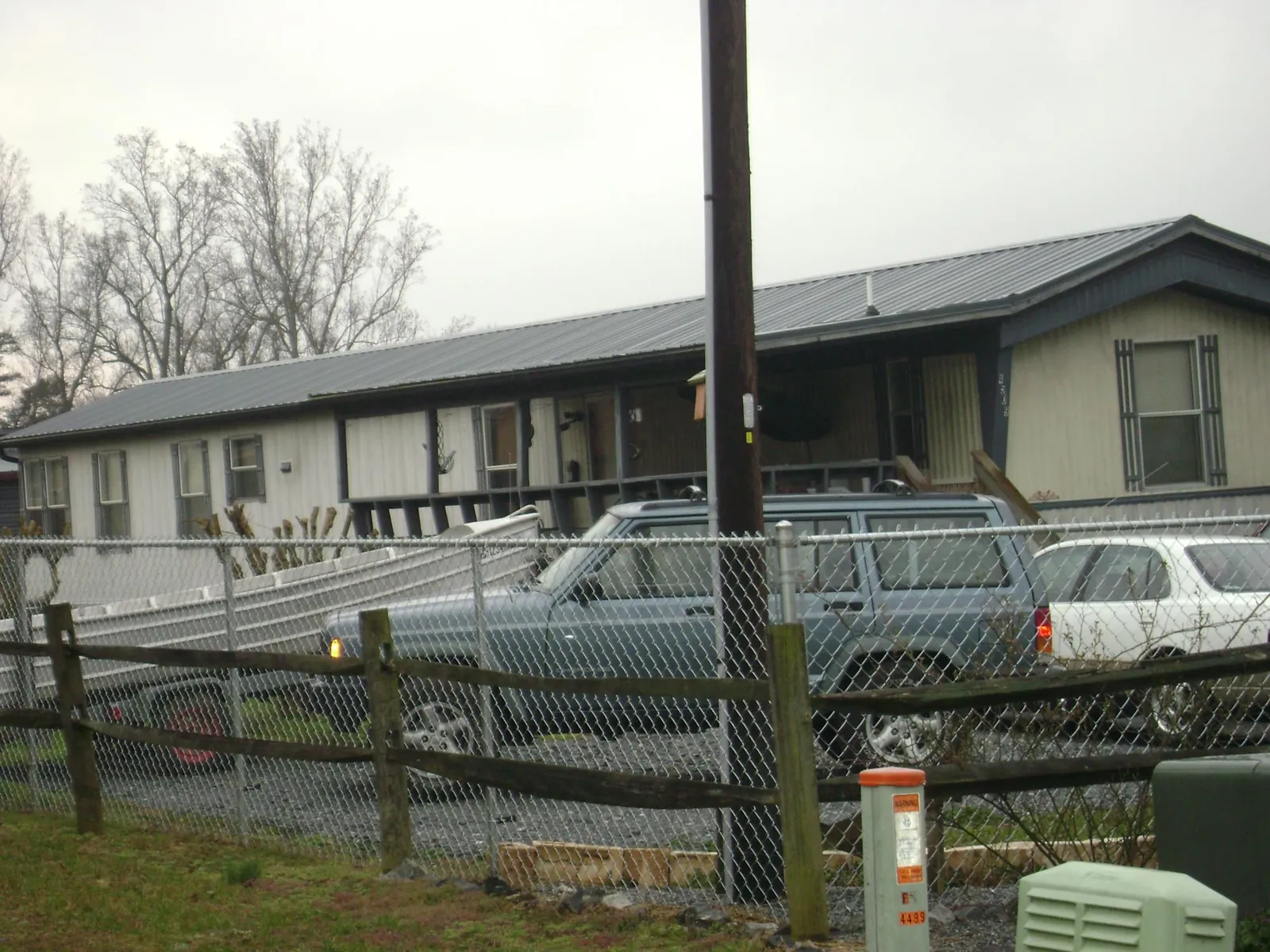 Dark metal roof on a long single story building behind a chain link fence in Mount Vernon